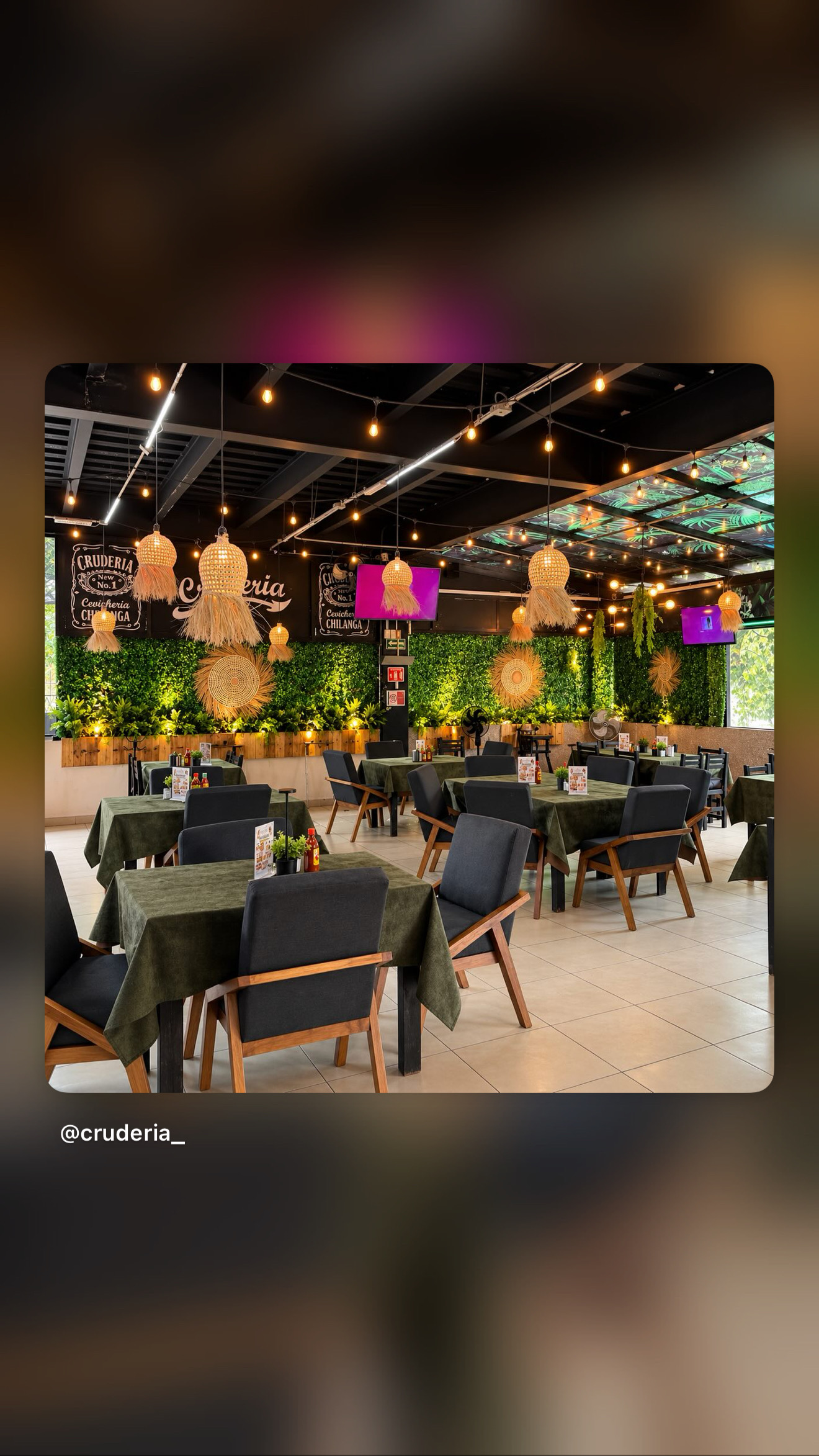 Interior de Cruderia, con mesas verdes, vegetación e iluminación cálida